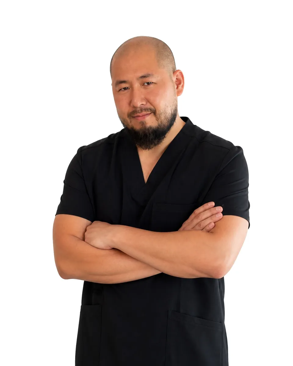 Portrait of Tony, a New York State licensed massage therapist, in black scrubs with his arms crossed